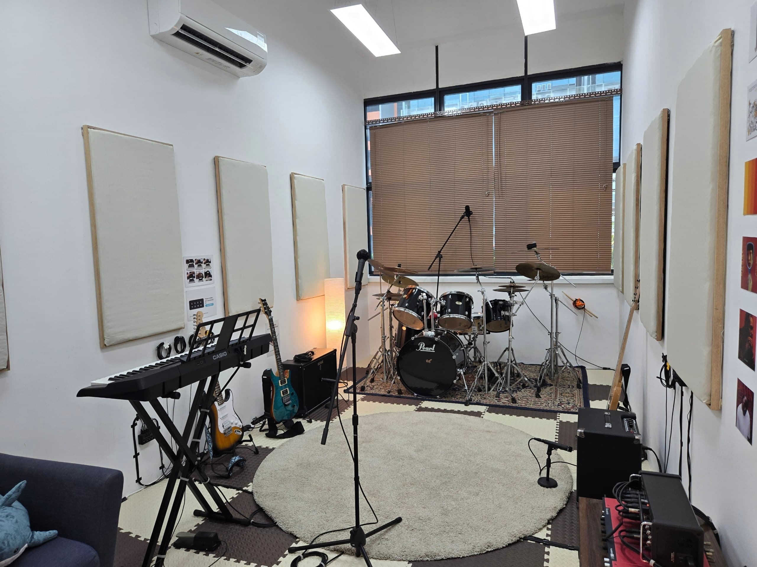 Wide view of the rehearsal room with drum kit, keyboard, and amps
